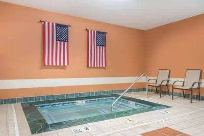 a hot tub in a room with two american flags at Ramada by Wyndham Catlettsburg Ashland in Catlettsburg