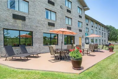 a patio with chairs and tables and umbrellas in front of a building at Ramada by Wyndham Catlettsburg Ashland in Catlettsburg