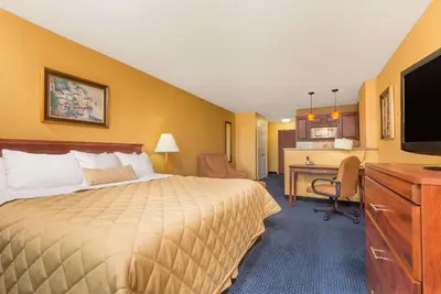 a hotel room with a bed and a desk with a computer at Ramada by Wyndham Catlettsburg Ashland in Catlettsburg