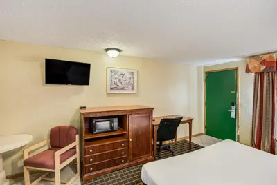 a hotel room with a bed and a desk and a tv at Knights Inn Ashland in Ashland