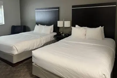 two beds in a hotel room with white sheets at Comfort Inn Huntington near University area in Huntington