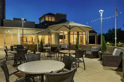a patio with tables and chairs and an umbrella at Hilton Garden Inn Cleveland Airport in Fairview Park