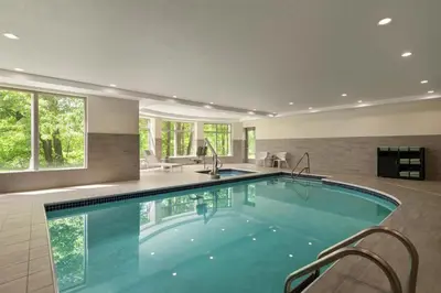 a large swimming pool in a house with chairs and windows at Hilton Garden Inn Cleveland Airport in Fairview Park