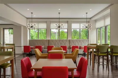 a restaurant with tables and chairs and windows at Hilton Garden Inn Cleveland Airport in Fairview Park