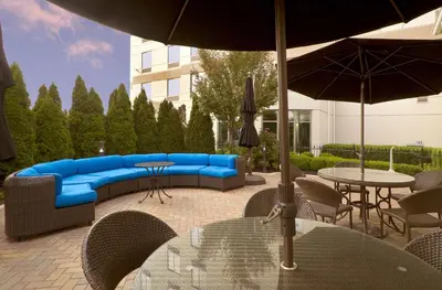 a patio with a blue couch and chairs and an umbrella at Hilton Garden Inn Columbus-University Area in Columbus