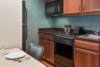 a kitchen with wooden cabinets and a black dishwasher at Homewood Suites by Hilton Cleveland-Beachwood in Beachwood