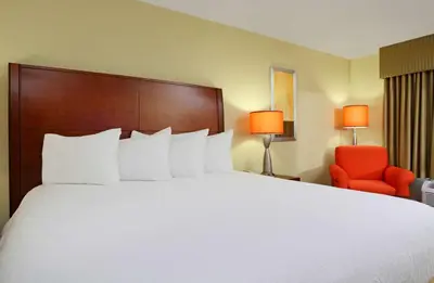 a hotel room with a large bed and a red chair at Hilton Garden Inn Columbus Airport in Columbus