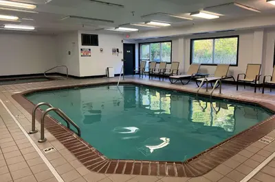 a swimming pool in a room with chairs and tables at Quality Inn Huntington University Area in Huntington