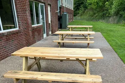 three picnic tables sitting outside of a brick building at Quality Inn Huntington University Area in Huntington