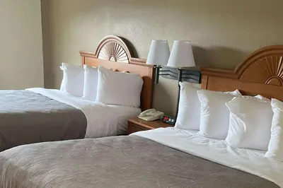 two beds with white pillows in a hotel room at Quality Inn Huntington University Area in Huntington