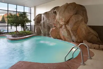 a large swimming pool with a rock waterfall at Embassy Suites by Hilton Columbus in Columbus