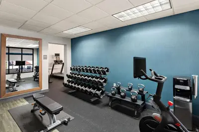 a gym with a blue wall with rows of exercise equipment at Hampton Inn Bridgeport/Clarksburg in Bridgeport