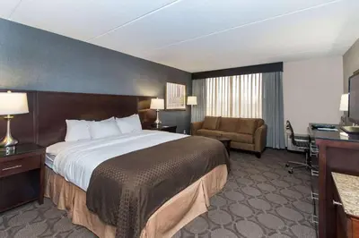 a hotel room with a large bed and a chair at Wyndham Columbus in Worthington