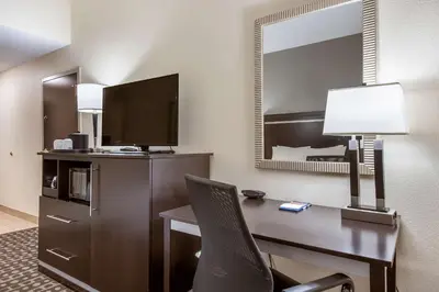 a hotel room with a desk with a television and a bed at Hampton Inn West in Columbus