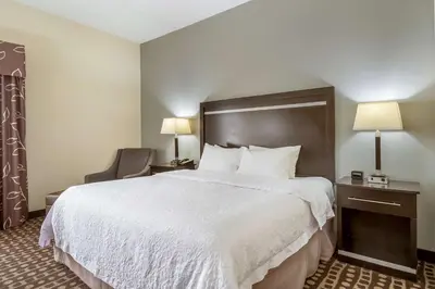 a hotel room with a large bed and a chair at Hampton Inn West in Columbus