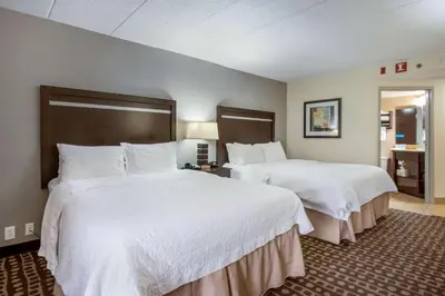 a hotel room with two beds with white sheets at Hampton Inn West in Columbus