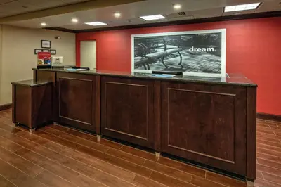 a reception desk in a room with a red wall at Hampton Inn Cambridge in Cambridge