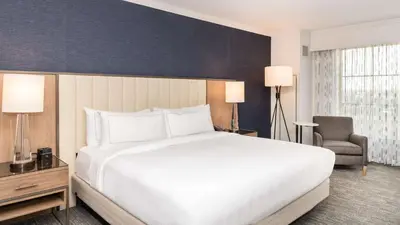 a bedroom with a large white bed and a chair at Hilton Columbus/Polaris in Columbus