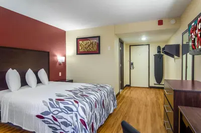 a hotel room with a large bed and a dresser at Red Roof Inn Perrysburg in Perrysburg
