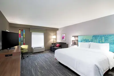 a hotel room with a bed and a flat screen tv at Hampton Inn Weston, WV in Weston