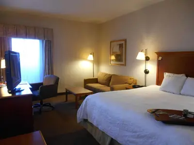 a hotel room with a bed and a couch and a television at Hampton Inn Columbus-International Airport in Gahanna