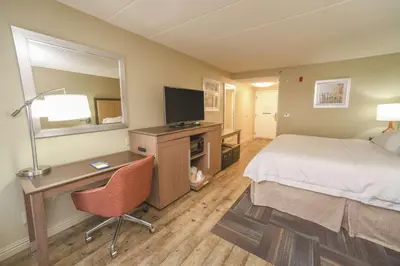 a hotel room with a bed and a desk with a television at Hampton Inn Cincinnati Eastgate in Eastgate