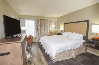a hotel room with a bed and a flat screen tv at Hampton Inn Cincinnati Eastgate in Eastgate