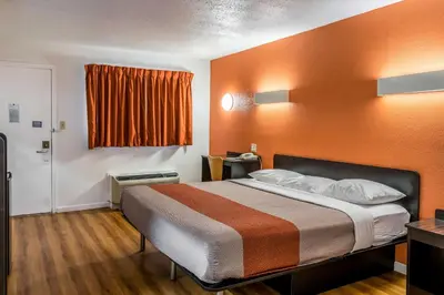 a hotel room with a bed with an orange wall at Motel 6 Florence, KY - Cincinnati Airport in Florence