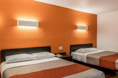 two beds in a hotel room with orange walls at Motel 6 Florence, KY - Cincinnati Airport in Florence