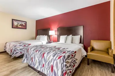 a hotel room with two beds and a chair at Red Roof Inn Dry Ridge in Dry Ridge
