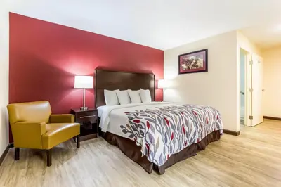 a hotel room with a bed and a chair at Red Roof Inn Dry Ridge in Dry Ridge