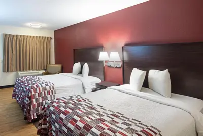 two beds in a hotel room with red walls at Red Roof Inn Cincinnati East - Beechmont in Cherry Grove