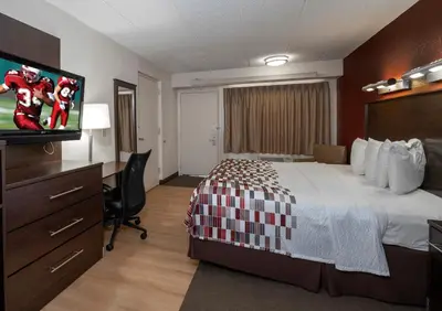 a hotel room with a bed and a flat screen tv at Red Roof Inn Cincinnati East - Beechmont in Cherry Grove