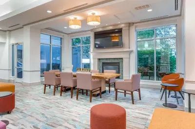 a dining room with a table and chairs and a fireplace at Hilton Garden Inn Cincinnati/Sharonville in Sharonville
