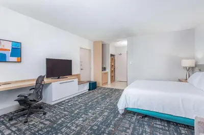a hotel room with a bed and a desk with a television at Hilton Garden Inn Cincinnati/Sharonville in Sharonville