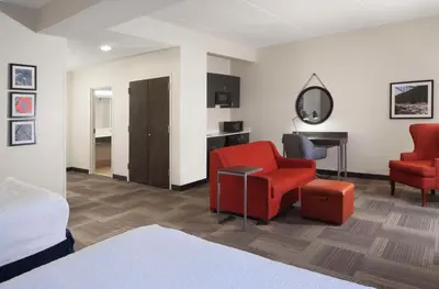 a hotel room with a bed and two chairs and a desk at Hampton Inn Charleston-Southridge in Charleston