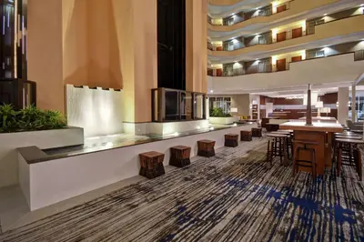 a lobby of a hotel with a bar and stools at Embassy Suites Charleston in Charleston