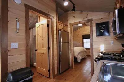a kitchen with a refrigerator and a bedroom in a log cabin at The Cayo Cabin, Millersburg Ohio in Millersburg