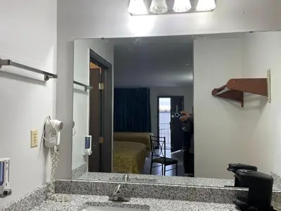 a mirror in a bathroom with a sink and a bedroom at Deerfield Inn in Xenia