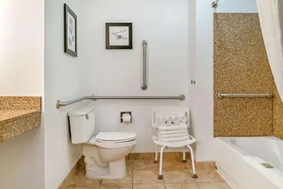 a bathroom with a toilet and a chair in it at Country Inn & Suites by Radisson, Rossford - Toledo South in Rossford