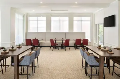a conference room with tables and chairs and a projection screen at Hilton Garden Inn Fort Wayne in Fort Wayne