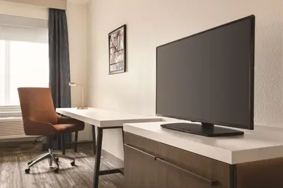 a room with a tv on a desk with a table and a chair at Hilton Garden Inn Fort Wayne in Fort Wayne