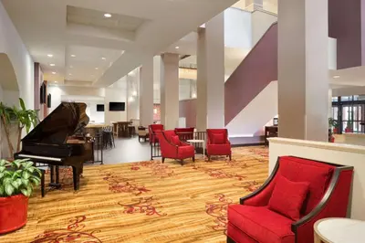 a lobby with a piano and red chairs at Hilton Fort Wayne at the Grand Wayne Convention Center in Fort Wayne
