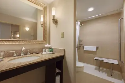 a bathroom with a sink and a toilet and a mirror at Hilton Fort Wayne at the Grand Wayne Convention Center in Fort Wayne