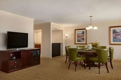 a living room with a dining room table and a flat screen tv at Hilton Fort Wayne at the Grand Wayne Convention Center in Fort Wayne
