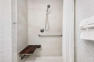 a shower with a wooden bench in a bathroom at Hampton Inn & Suites Fort Wayne-North in Fort Wayne