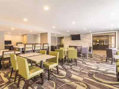 a dining room with tables and chairs and a tv at La Quinta by Wyndham Cleveland - Airport North in Cleveland