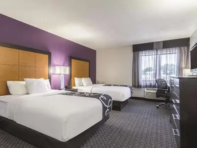 two beds in a hotel room with purple walls at La Quinta by Wyndham Cleveland - Airport North in Cleveland