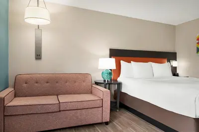 a bedroom with a bed and a chair and a lamp at La Quinta Inn by Wyndham Columbus Dublin in Dublin