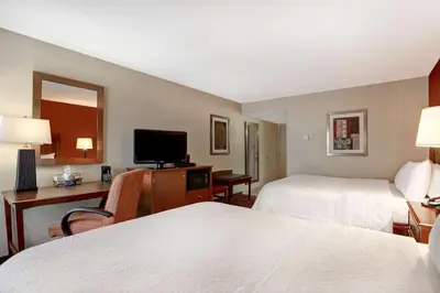 a hotel room with two beds and a desk and a television at Hampton Inn Fort Wayne-Southwest in Fort Wayne